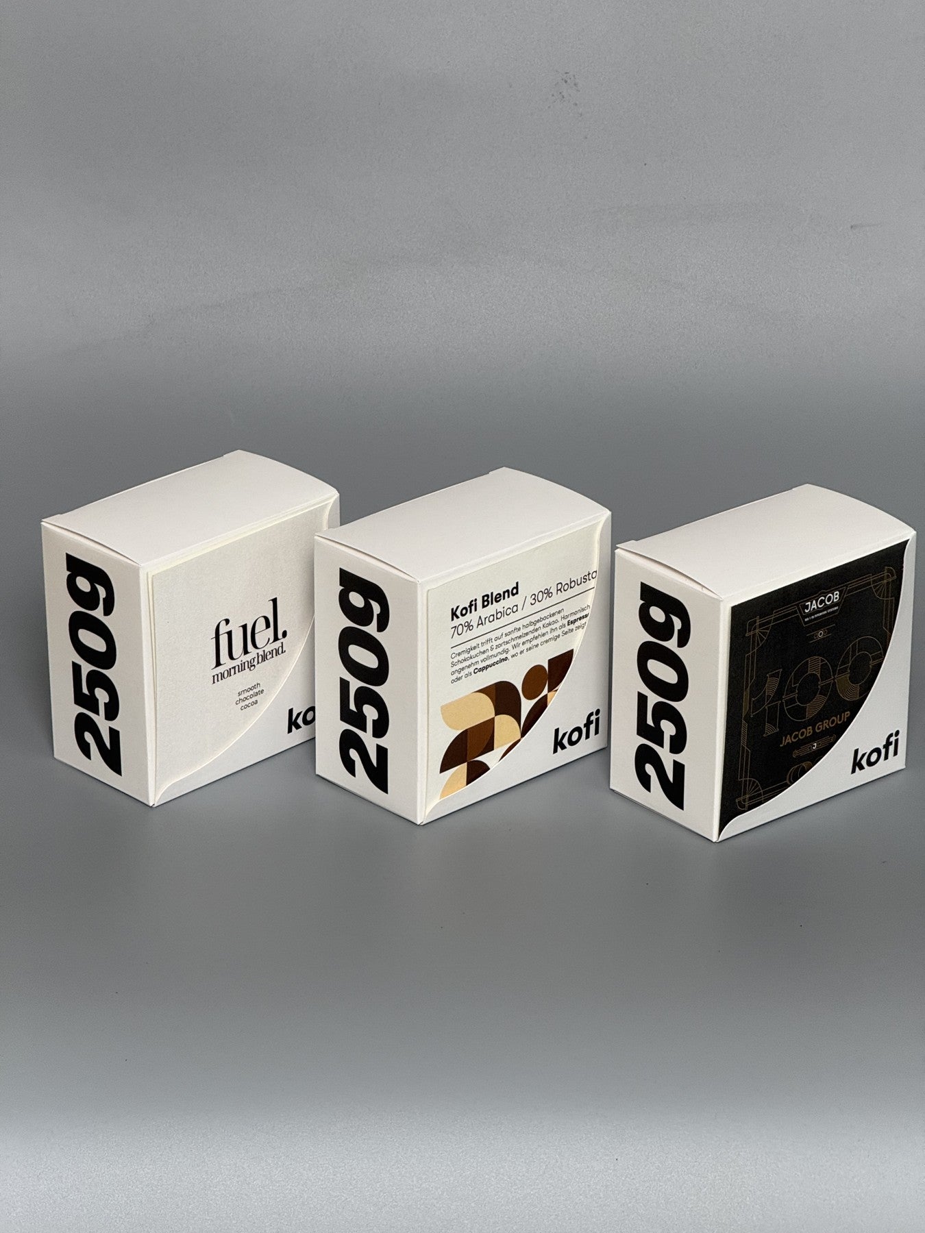 Drei echte 250-g-Kaffeeboxen aus schräger Perspektive: bedruckte Fronten und Seiten